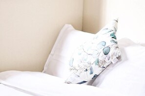 A bed with white bedding and a floral pillow. - LAN A (Osaka)