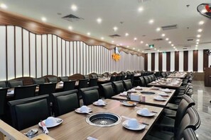 A long dining table with multiple chairs, a central hot plate, and a modern ceiling design.