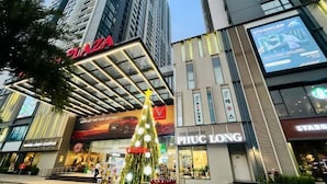 A modern building with a prominent 'Piazza' sign, a Christmas tree, and storefronts including 'PHUC LONG'. - Sophia Housing - Vinhomes Sky Lake Pham Hung (Hanoi)
