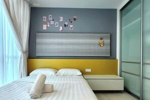 A hotel room with a bed, a headboard, a bedside table, and a window with curtains. - Modern Suite in Penang Island (George Town)