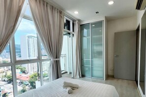 Een hotelkamer met een groot raam, een bed, een schuifdeur en uitzicht op de stad.