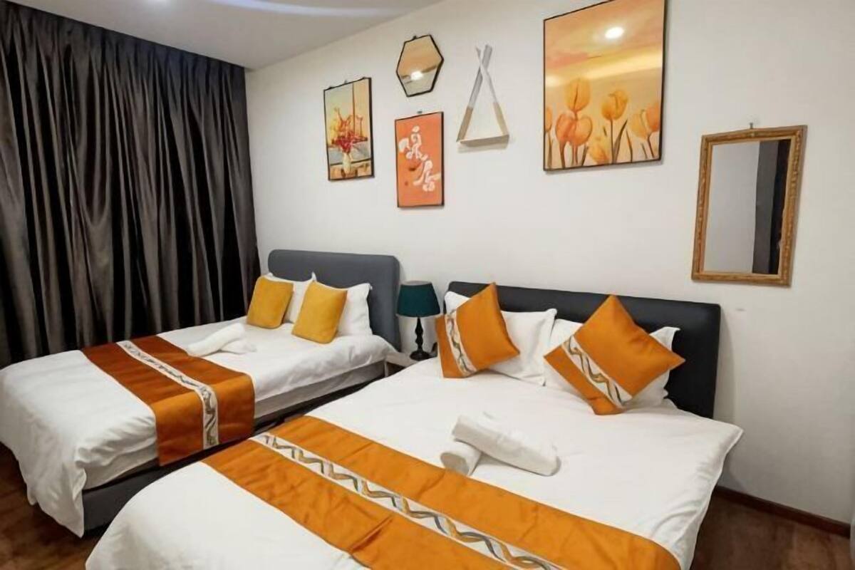 A hotel room with two beds, each with white bedding and orange accents, a dark headboard, and artwork on the walls.