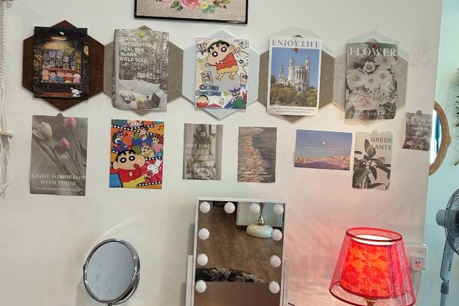 A wall with various framed pictures and a vanity mirror with lights.