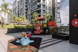 Zona de juegos infantiles con toboganes y una estructura de juego con forma de tiburón azul.