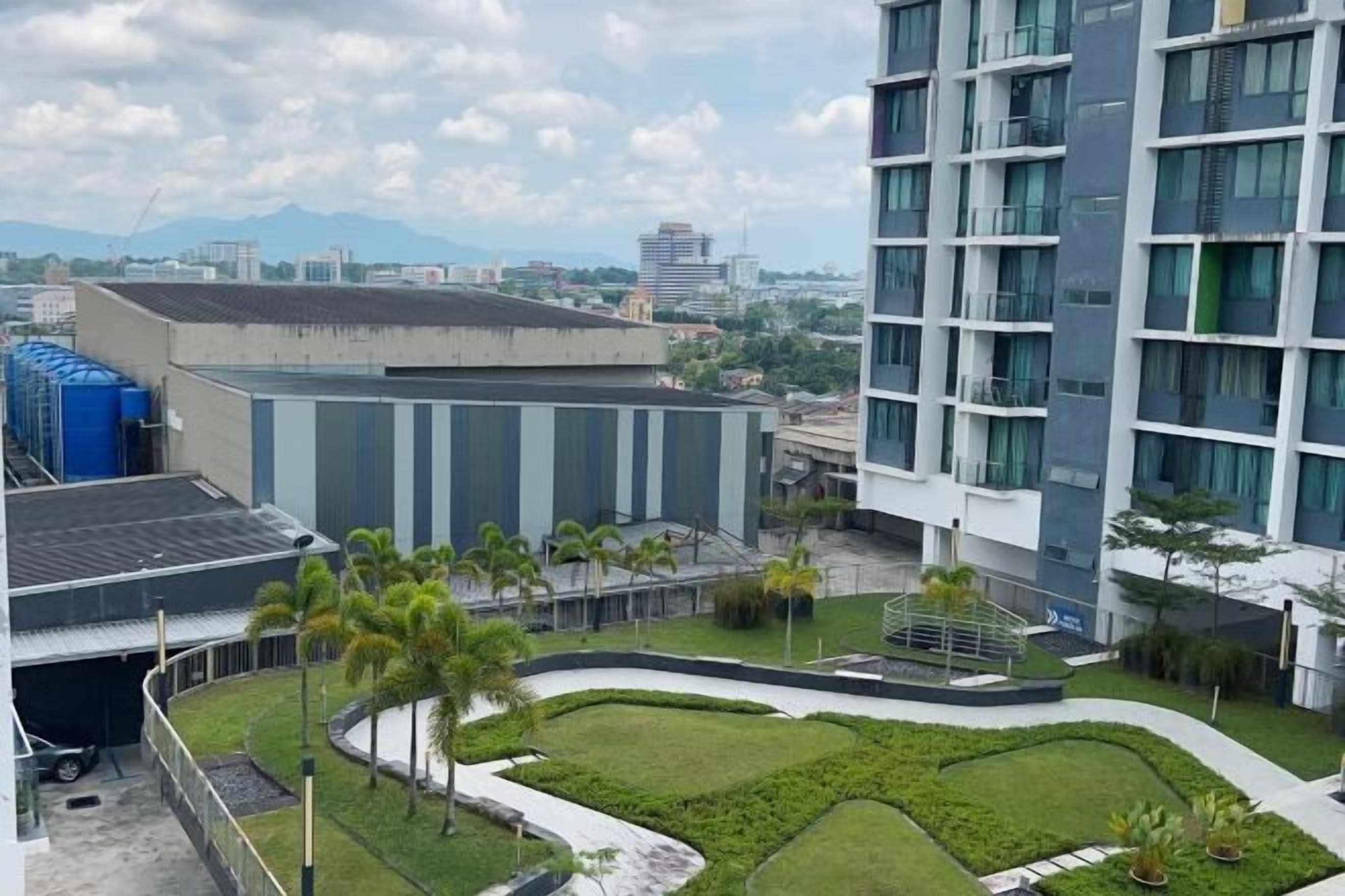 A modern building with a rooftop solar panel array, a landscaped courtyard with palm trees, and a view of distant mountains.