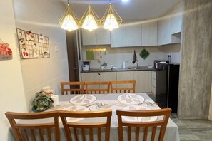 A dining area with a table set for four, wooden chairs, and a kitchen in the background. - Vivacity Jazz 3 , 2-8 pax, lvl 9 (Kuching)