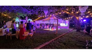 Evento al aire libre con una carpa y luces colgantes.