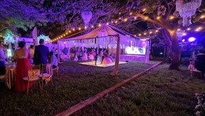 Evento al aire libre con una carpa y luces colgantes.
