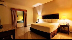 Una habitación de hotel con cama, lámparas de noche, escritorio y espejo.