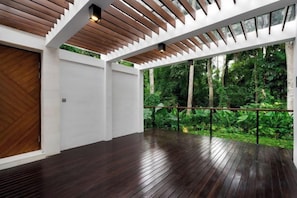 An indoor space with a wooden floor, white walls, and a view of a lush garden through large windows. - Villa Arcadia by BaliSuperHost (Bali)