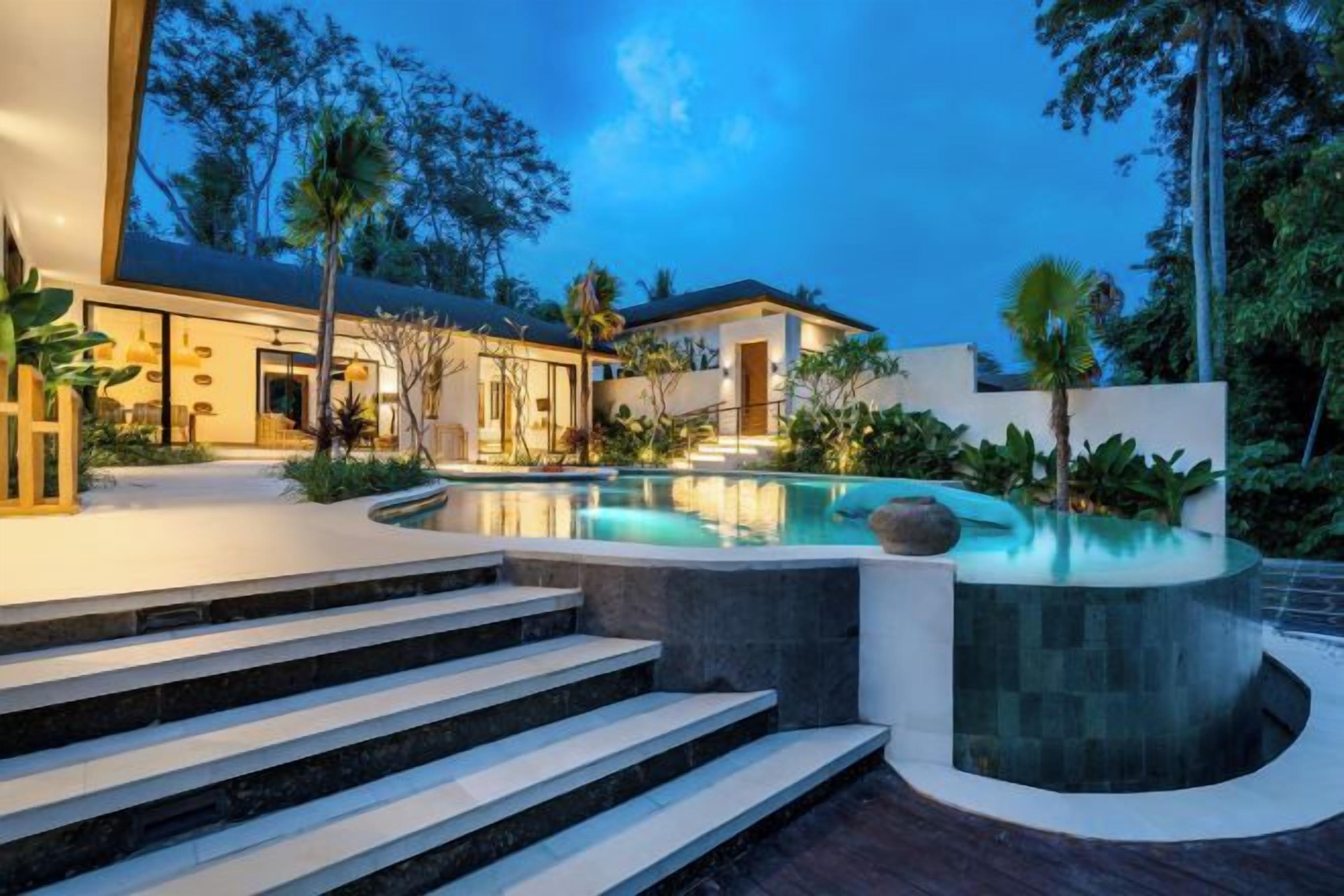 A modern house with a swimming pool, steps leading to the pool, and a well-maintained garden.