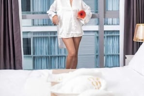 A hotel room with a large window, a bed with white bedding, and a nightstand with a lamp. - Luxury Penthouse hotel near City of Dreams Solaire Okada NAIA MOA- 1812 (Paranaque)