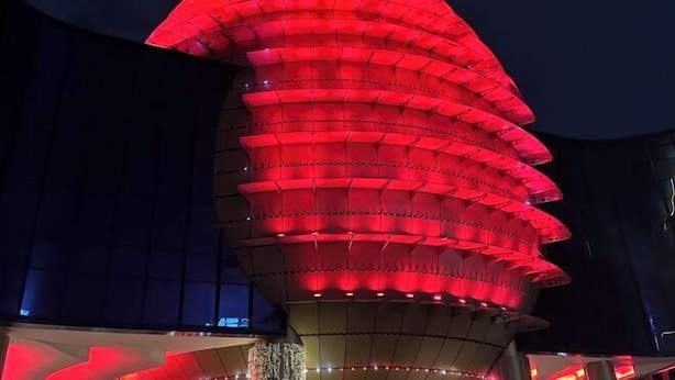 Um edifício moderno com uma estrutura de telhado escalonada e iluminada em vermelho.