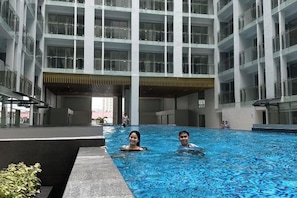 An indoor swimming pool with a modern building in the background. - Luxury Penthouse hotel near City of Dreams Solaire Okada NAIA MOA- 1812 (Paranaque)