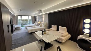 Quarto de hotel moderno com uma cama grande, um sofá, uma mesa de jantar e uma cadeira de massagem.