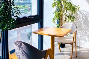 A modern room with a large window, a wooden table, a white chair, and a potted plant. - Terra Hotel Kawit (Kawit)