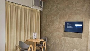 A room with a bed, a table with two chairs, a TV mounted on the wall, and a sign prohibiting smoking. - Terra Hotel Kawit (Kawit)
