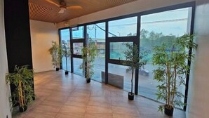 A spacious interior with large windows, potted plants, and a ceiling fan. - Terra Hotel Kawit (Kawit)