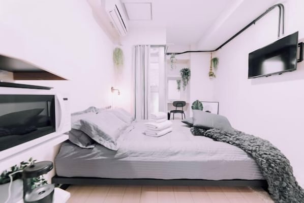 Un dormitorio moderno con cama, televisor, escritorio y silla.