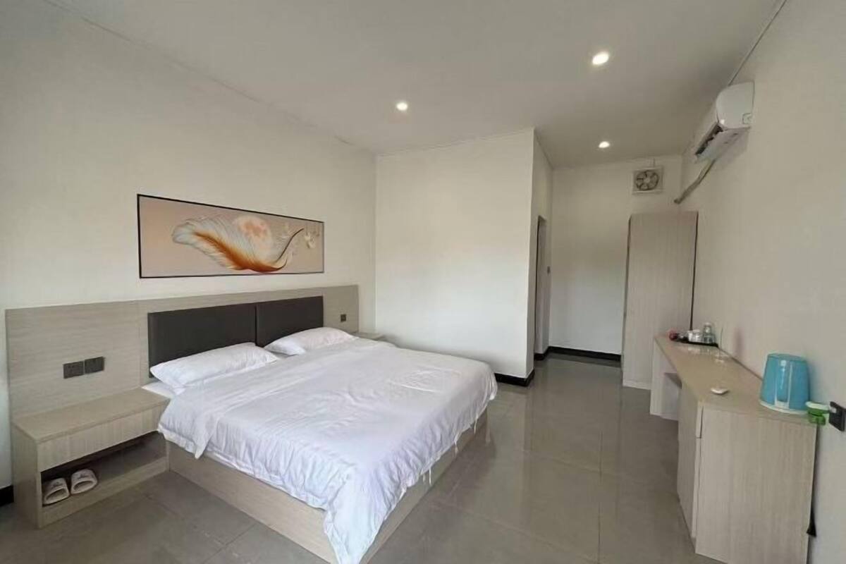 Ein modernes Hotelzimmer mit Bett, Nachttisch und Wand-Klimaanlage.