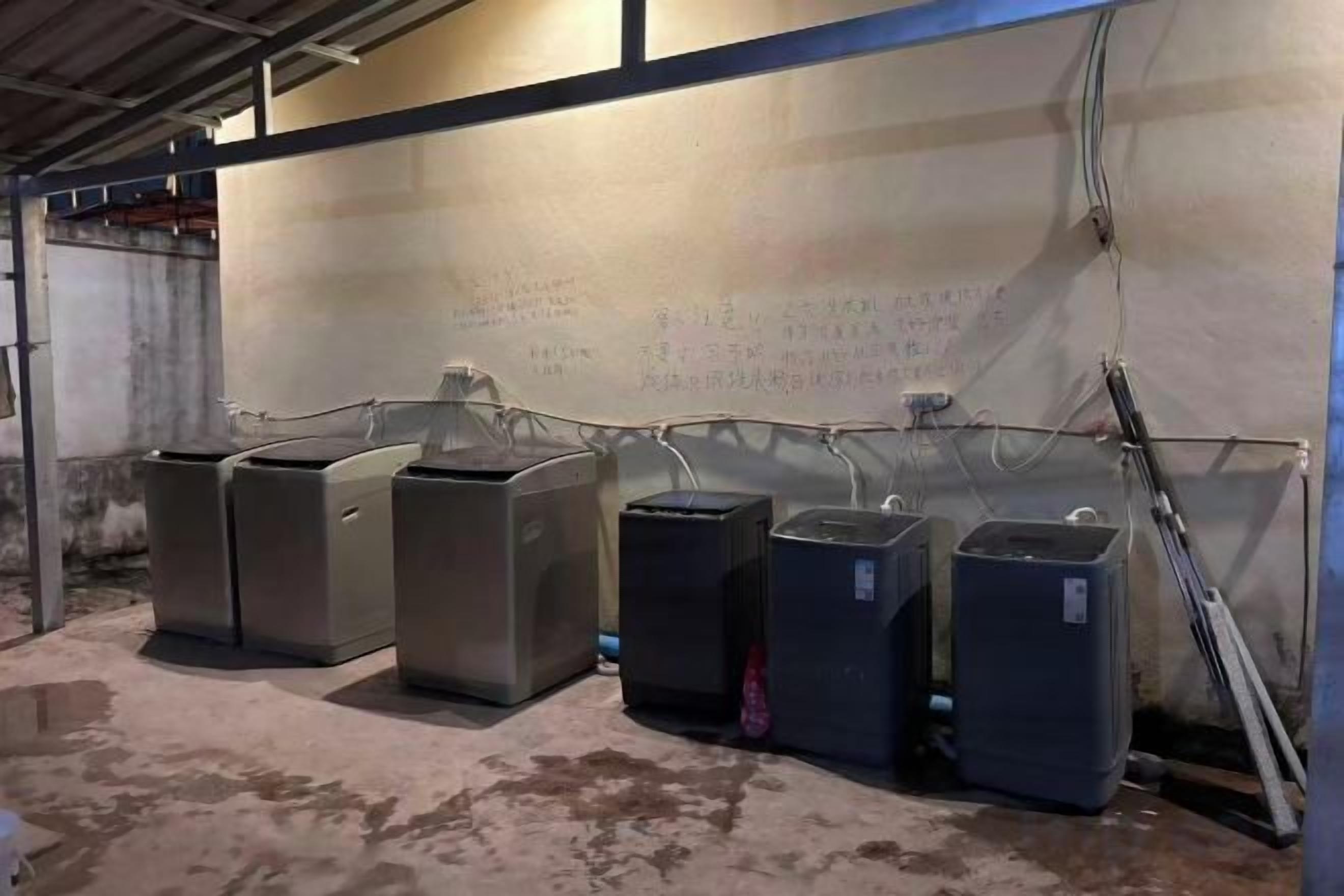 A row of industrial-style trash bins lined up against a wall with visible electrical wiring.