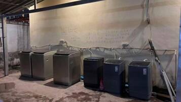 A row of industrial-style trash bins lined up against a wall with visible electrical wiring.