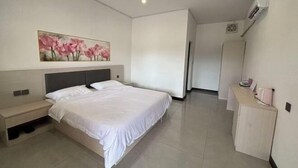 A modern hotel room with a large bed, a bedside table, a small desk, and a painting on the wall. - Dong 'Du Da Jiu Dian (Vientiane)
