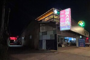 Rakennuksessa on suuri, valaistu kyltti, katettu sisäänkäynti ja selvästi näkyvä liiketila.