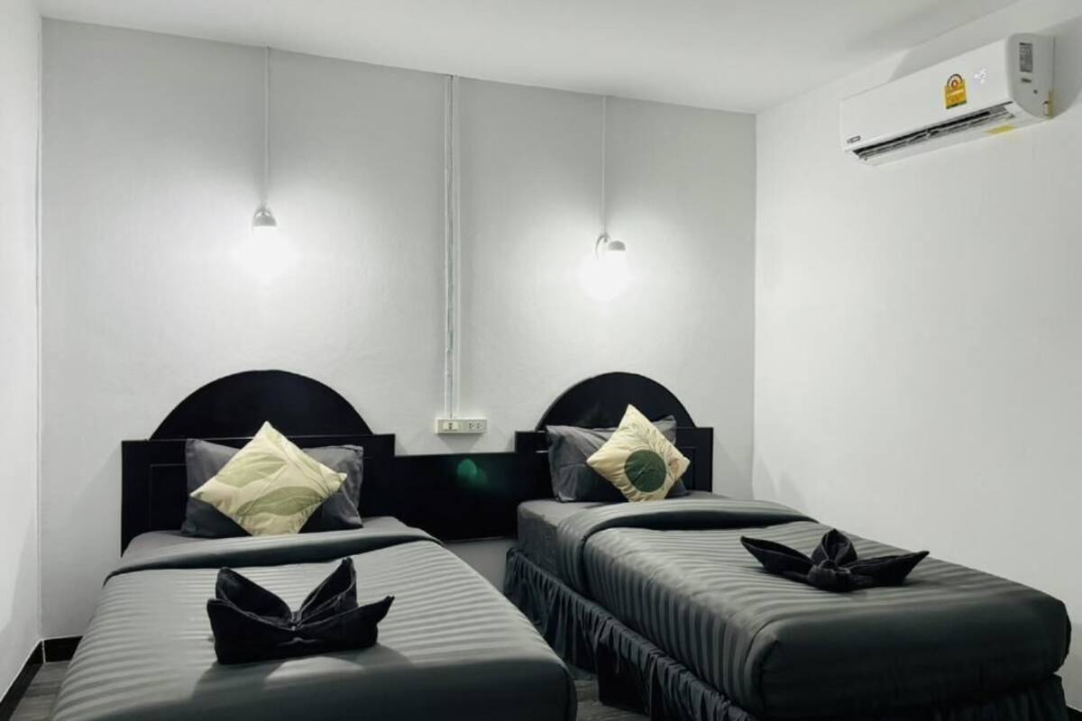 Ein Hotelzimmer mit zwei Betten, einem Flachbildfernseher, einer Klimaanlage und einer Wandleuchte.