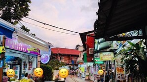 A street with various shops, including a visible pharmacy and a food stall. - White House (Ko Phi Phi)