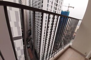 A high-rise building with a metal balcony railing, a construction crane in the background, and a view of other buildings. - FLC green 18 Pham Hung - 2Br - 800m to Landmark 72 (Hanoi)