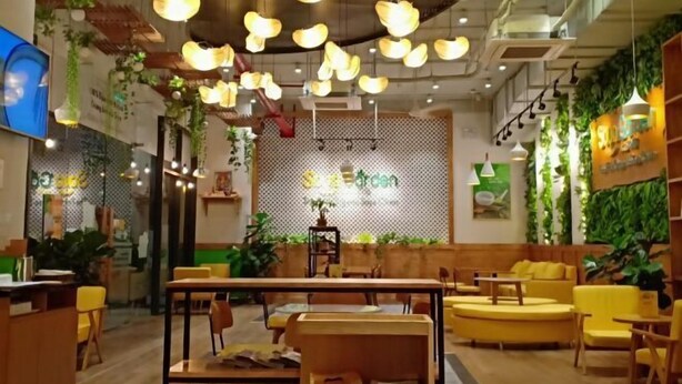Een modern café interieur met houten meubels, hangende hanglampen en groene planten.