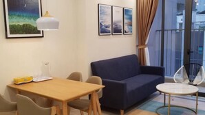 Een gezellige zithoek met een houten tafel, twee stoelen, een blauwe bank en een kleine ronde tafel.