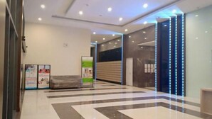 Een moderne lobby met een receptiebalie, een zithoek en een glazen wand met verticale LED-verlichting.