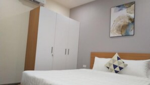 Een slaapkamer met een bed, een kledingkast en een schilderij aan de muur.