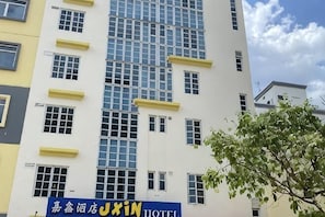 A hotel building with a blue sign reading 'XIN HOTEL' and multiple windows.
