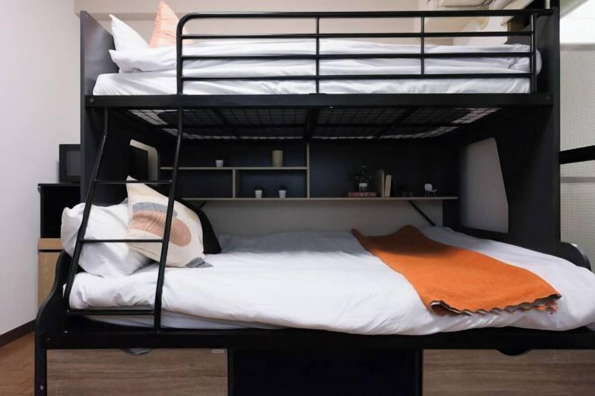 A bunk bed with a desk and shelving unit, a pillow, and a blanket.