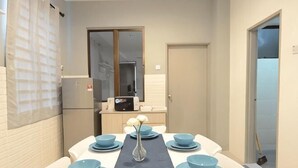 A dining area with a long table set with blue bowls and plates, a vase, and a small table with a computer. - De cozy Homestay (8-14 pax) (Ipoh)
