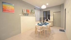 A dining area with a white table and chairs, a pendant light, and a door in the background. - De cozy Homestay (8-14 pax) (Ipoh)