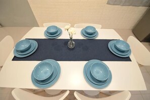 A rectangular dining table with a dark blue center runner, surrounded by white chairs. - De cozy Homestay (8-14 pax) (Ipoh)