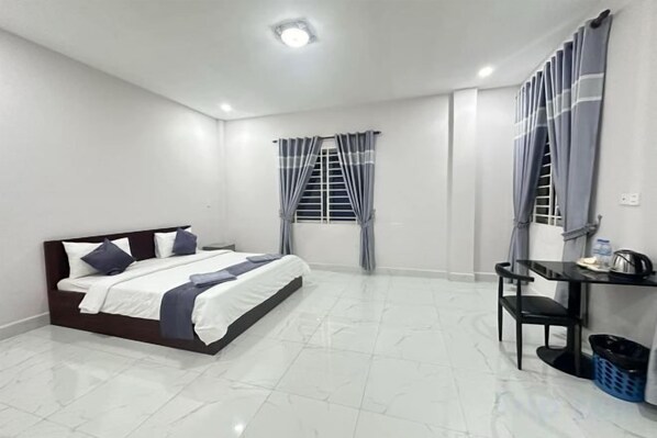 A bedroom with a bed, a desk, and a chair. - Rosi Guesthouse & Coffee3 (Sihanoukville)