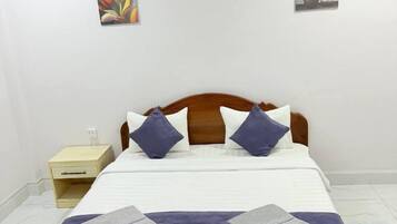 Una cama con cabecera de madera, dos almohadas y una manta.