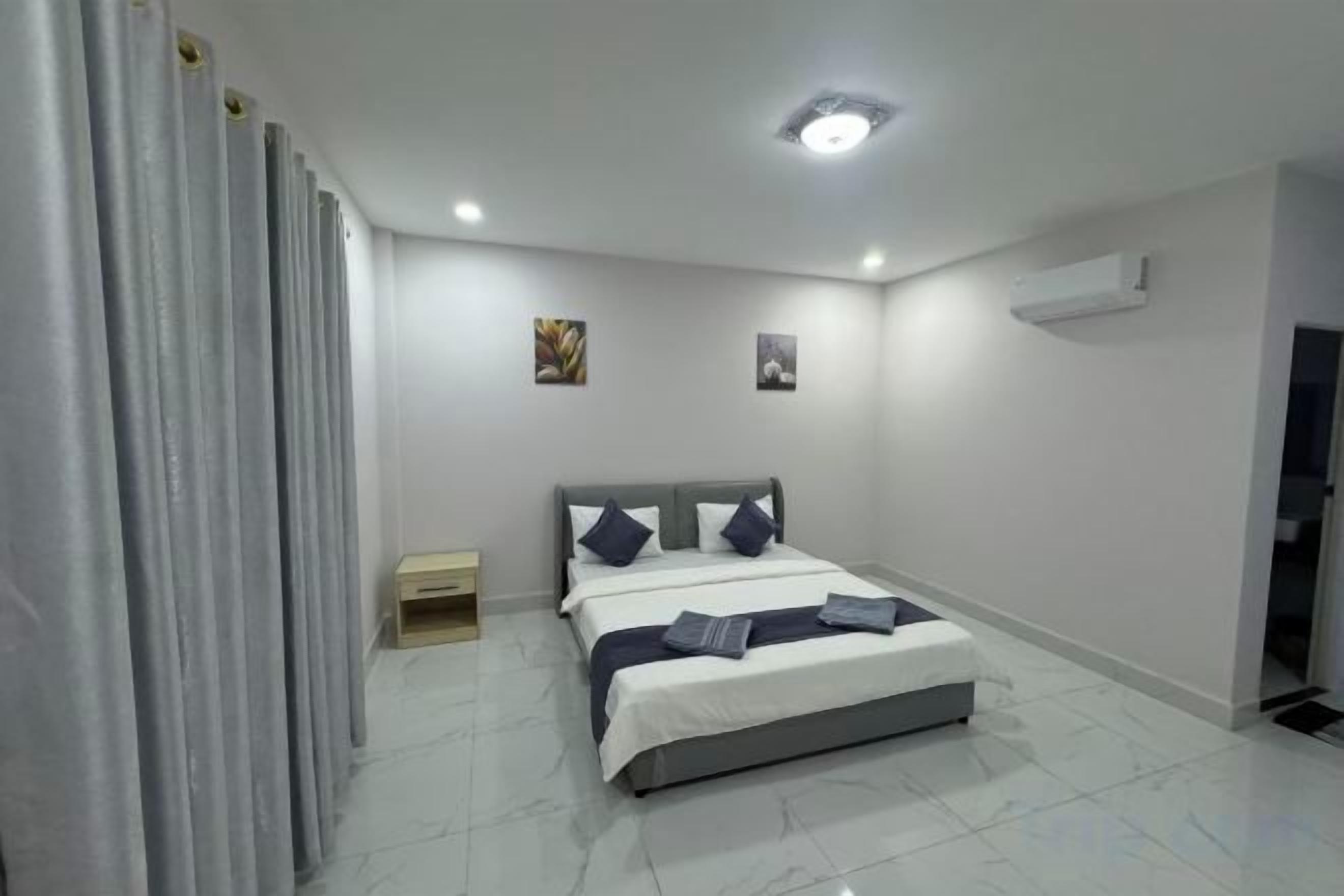 Une chambre à coucher comprenant un lit, une table de chevet, un climatiseur fixé au mur et une porte.