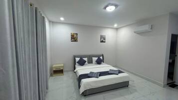 Une chambre à coucher comprenant un lit, une table de chevet, un climatiseur fixé au mur et une porte.