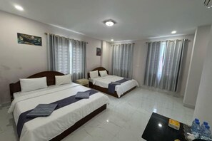 A hotel room with two beds, a nightstand, a table with water bottles, and curtains. - Rosi Guesthouse & Coffee3 (Sihanoukville)