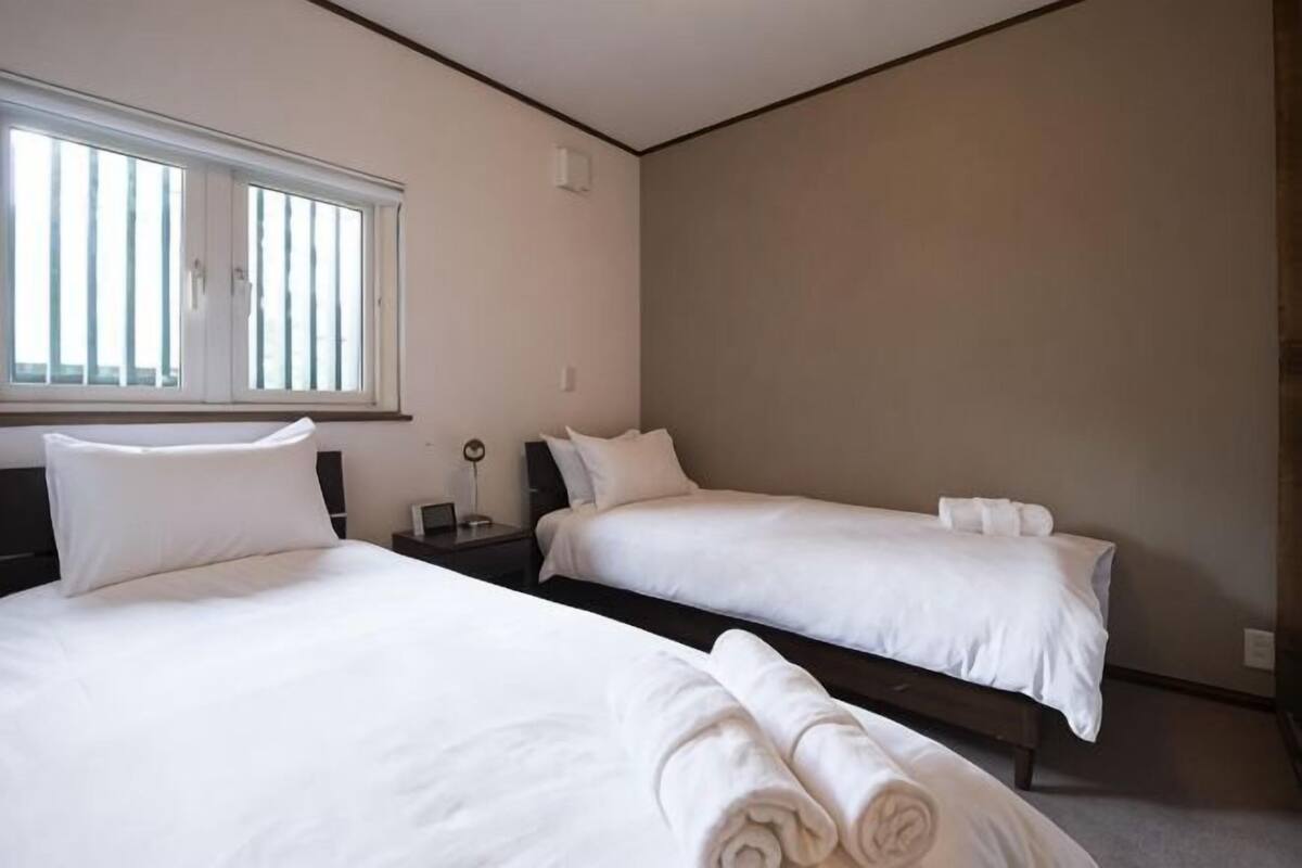 A hotel room with two beds, a window, and a nightstand.