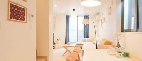 Una habitación de hotel moderna con comedor, sofá, ventana grande y lámpara.
