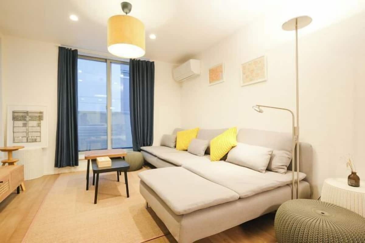 A modern living room with a sofa, a table, and a lamp.