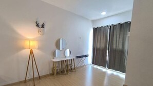 A room with a standing lamp, a round mirror, a small table with chairs, and a window with curtains. - D'Sara Sentral Condo (Petaling Jaya)