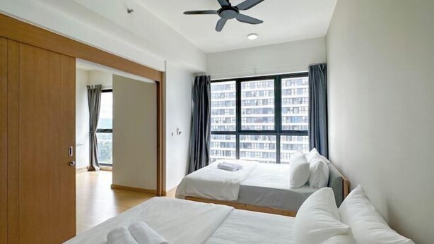 A hotel room with two beds, a ceiling fan, a large window with curtains, and a view of a cityscape. - D'Sara Sentral Condo (Petaling Jaya)